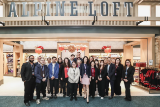 A group of people pose and smile in front of a retail store in Vancouver International Airport.
