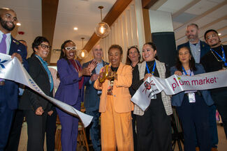 Group of people clap after cutting large white ribbon for new airport restaurant